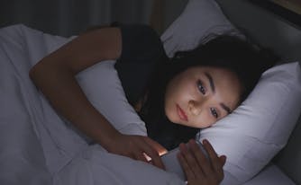 person scrolling through phone in bed