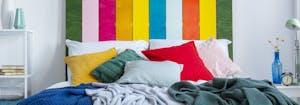 kindercore bedroom with yellow, green, gray, red, and pink pillows on top of bed