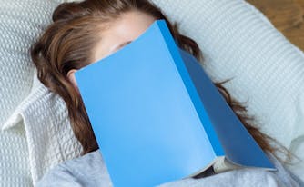image of woman with book over her face - sleep learning