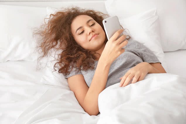 person looking at phone in bed