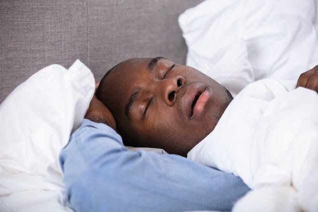 person snoring in bed, which can lead to a tension headache