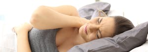 best pillow for back and neck pain - image of woman with neck pain sleeping on pillow