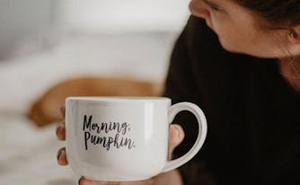 image of woman drinking coffee in bed - daylight saving time
