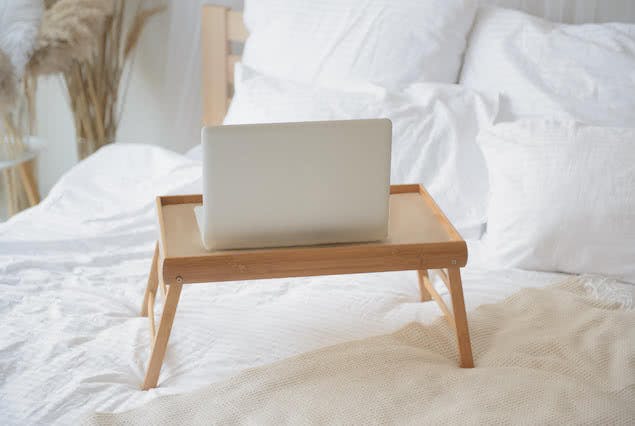laptop stand on bed with laptop on top of it