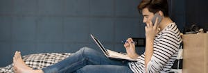 image of college student sitting on college dorm room bed