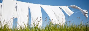 how to clean bedding - image of sheets drying on clothing line