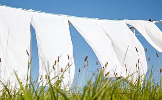 how to clean bedding - image of sheets drying on clothing line