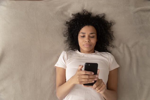 how to sleep through noise - person using phone in bed