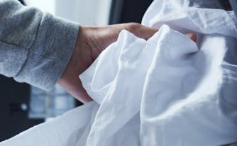 person putting sheets in washing machine to get blood out of sheets