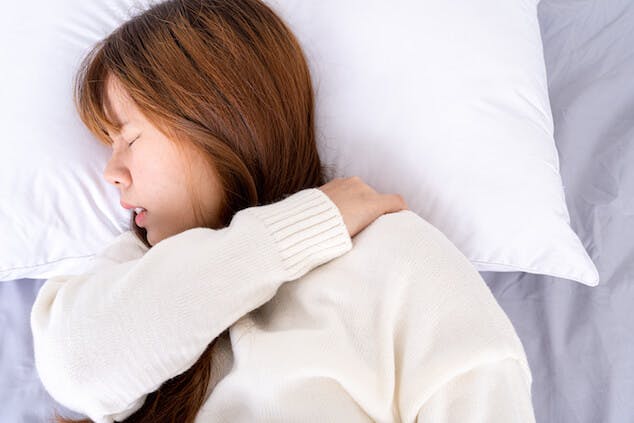 person with neck pain sleeping on pillow that needs to be replaced