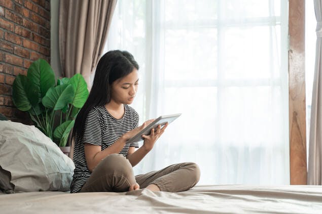 bedtime routine for teenagers - teen looking at tablet device in bed