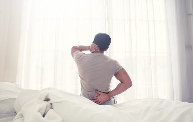 health effects of old mattress - person holding back in pain
