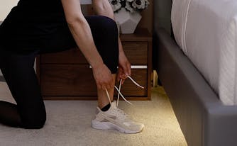 saatva mattress in runner's world - image of woman lacing up sneakers next to bed