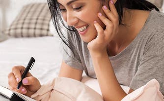 image of woman writing in journal in bed