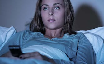 image of woman binge-watching tv from bed