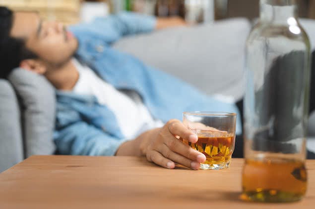 person holding whiskey glass and sleeping on couch