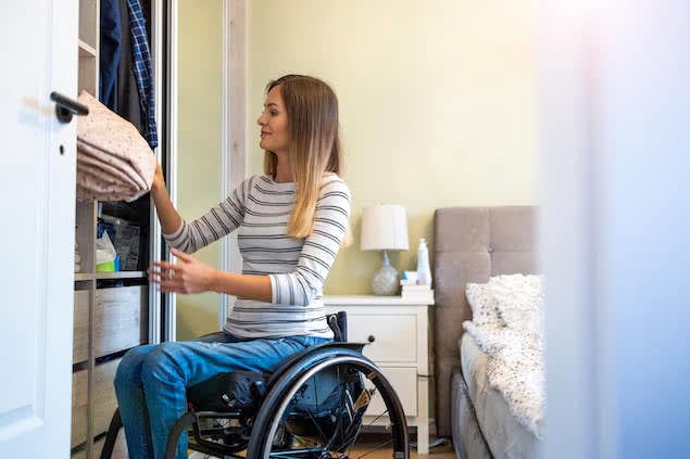 person in wheelchair putting sheets away in closet