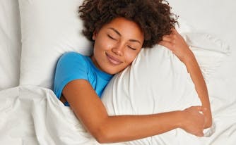 image of person hugging pillow in bed