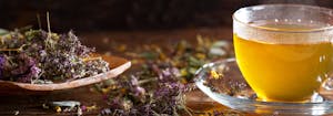 cup of herbal tea next to spoon with tea leaves on it