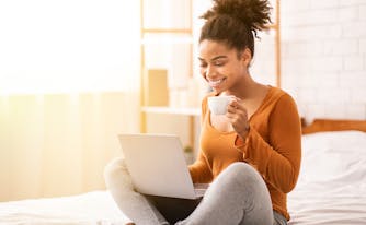 person drinking coffee in bed in the morning