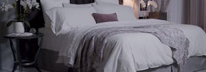 bedroom with a saatva mattress that has pillows and a gray throw blanket on top if it