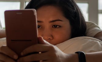 person looking at phone in bed