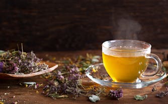cup of herbal tea next to spoon with tea leaves on it