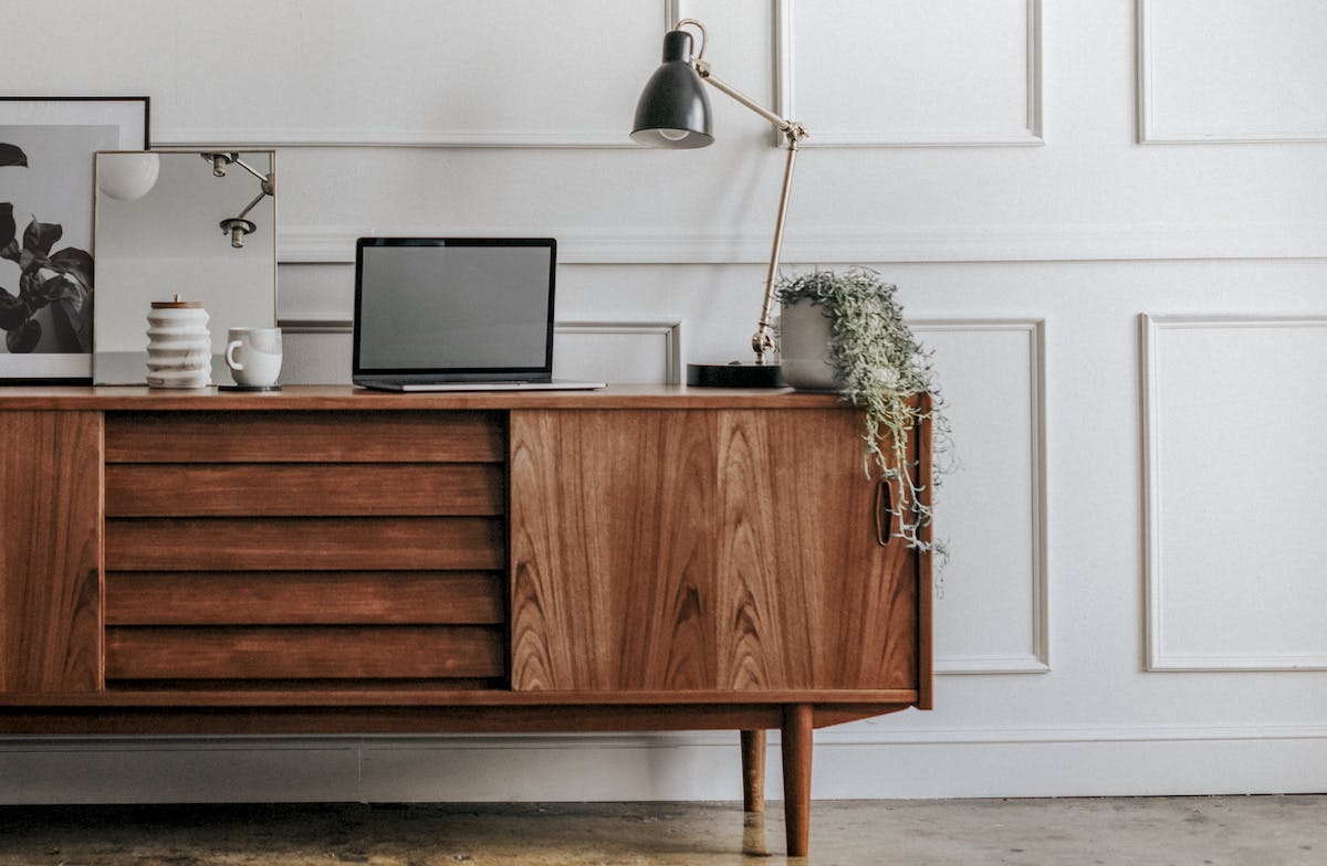 mid century modern table with mirror, laptop, and lamp on top of it