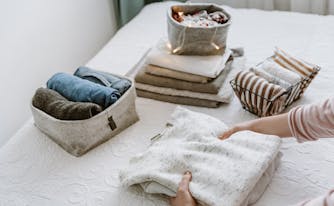 person spring cleaning with folded clothes in bins