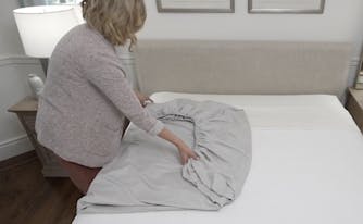 person folding a fitted sheet