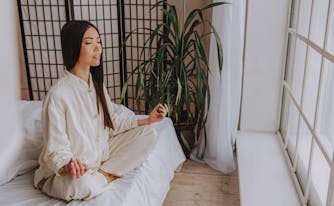 person meditating while in bed