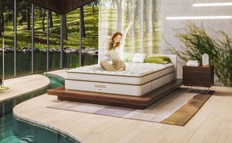 person sitting on saatva mattress in bedroom with nature all around them
