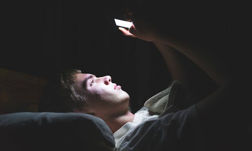 A teenager in bed at night looking at his cellphone