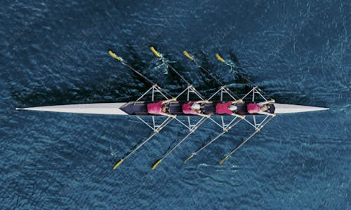 Rowing boat with a team on the water all paddling in the same direction for success.