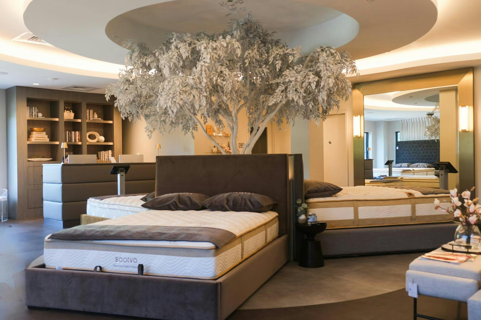 Saatva Westport's elegant mattress display surrounding a decorative tree, near their live customer service desk.