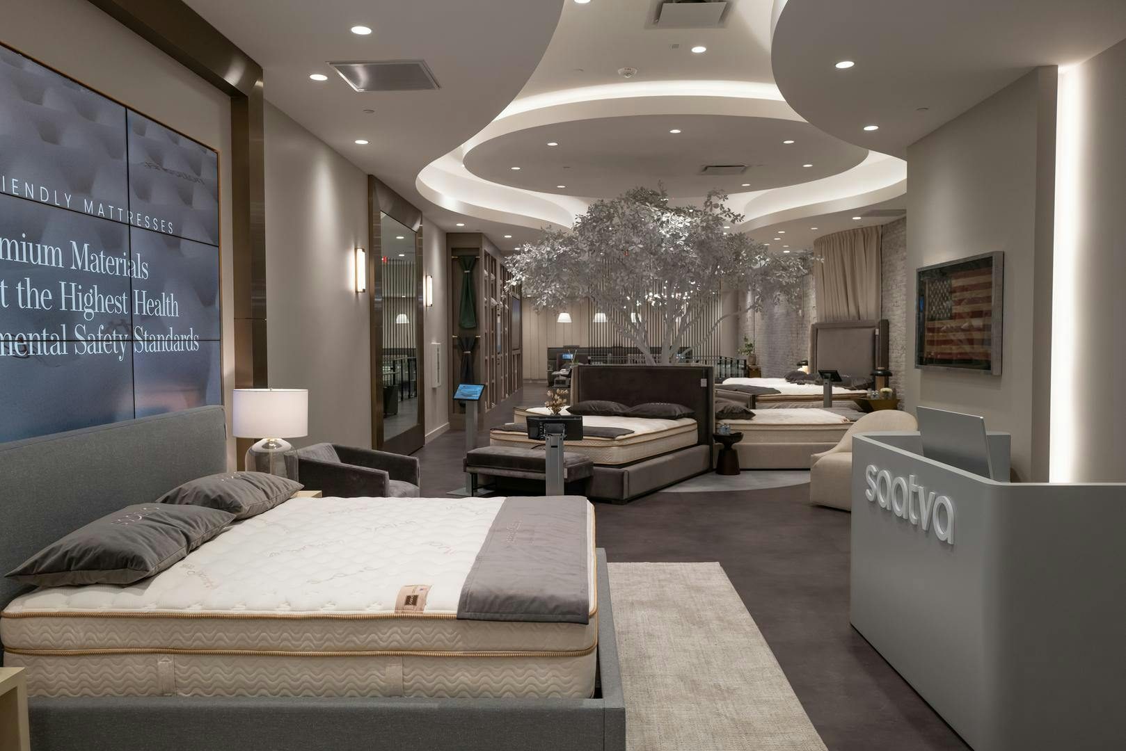 The elegant interior of the Saatva Flatiron retail location features a bed with a digital headboard and welcome desk where Sleep Guides help visitors on the shopping journey.