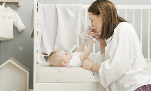 A mother and child enjoying time on Saatva's dual-phase, made-to-order Crib Mattress.