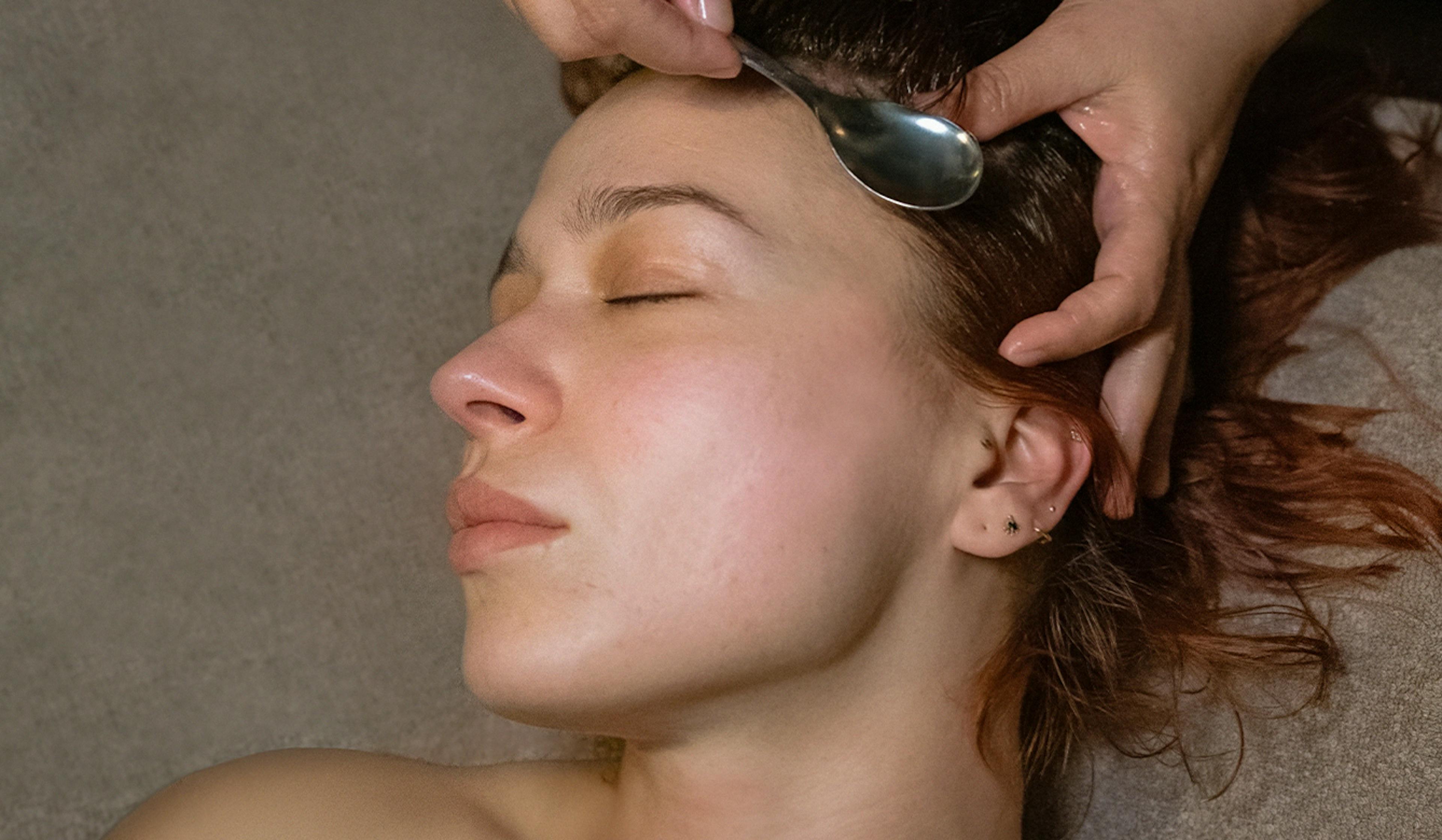 Therapist performing scalp and neck massage using warm oil — inspired by Ayurvedic techniques at Sabai Sabai studio in Split.