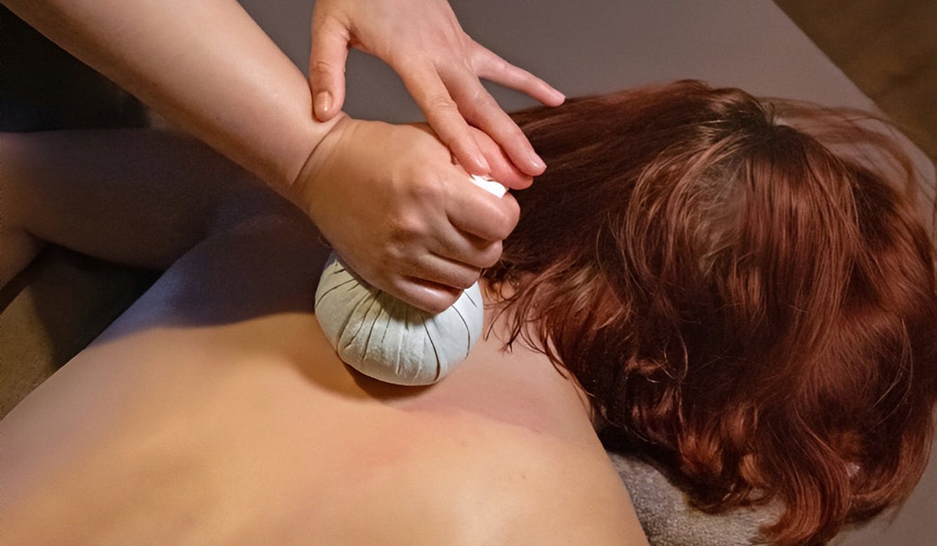 Therapist applying hot herbal compress on a client’s back at Sabai Sabai Thai Massage Split — natural Thai therapy for detox, relaxation, and improved circulation.