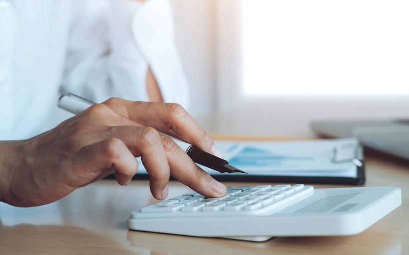 The hand of a man pressing numbers on a calculator at a desk