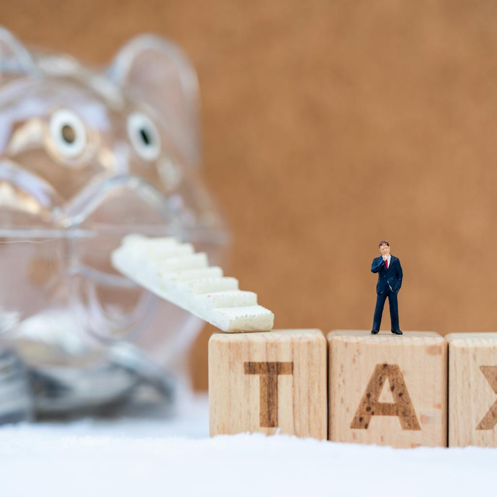 Bloques de letras en miniatura que deletrean TAX con una escalera mecánica que sube a una alcancía que está ahorrando dinero...