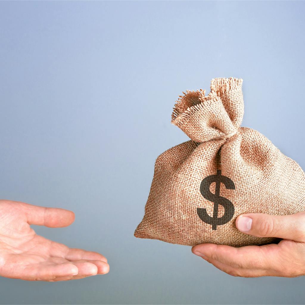 Man holds, gives a bag of money in hand like a bonus.