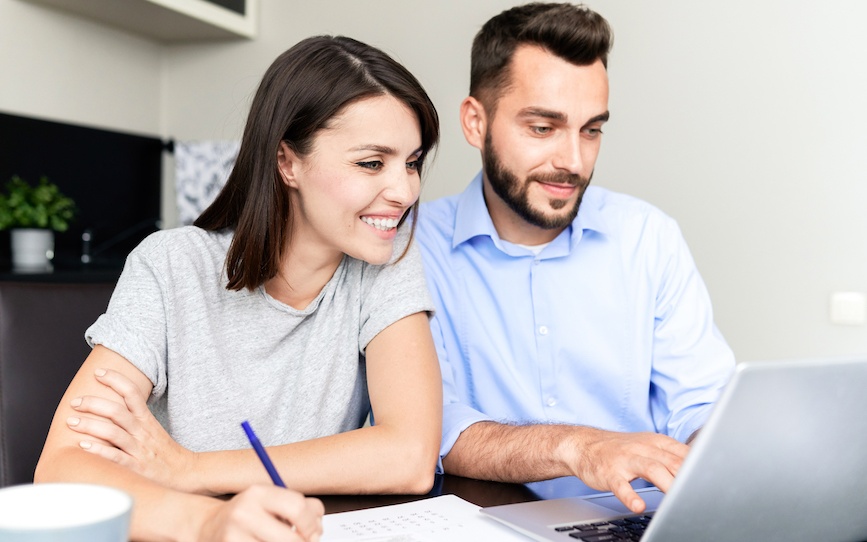 A couple filling up documents in front of the laptop