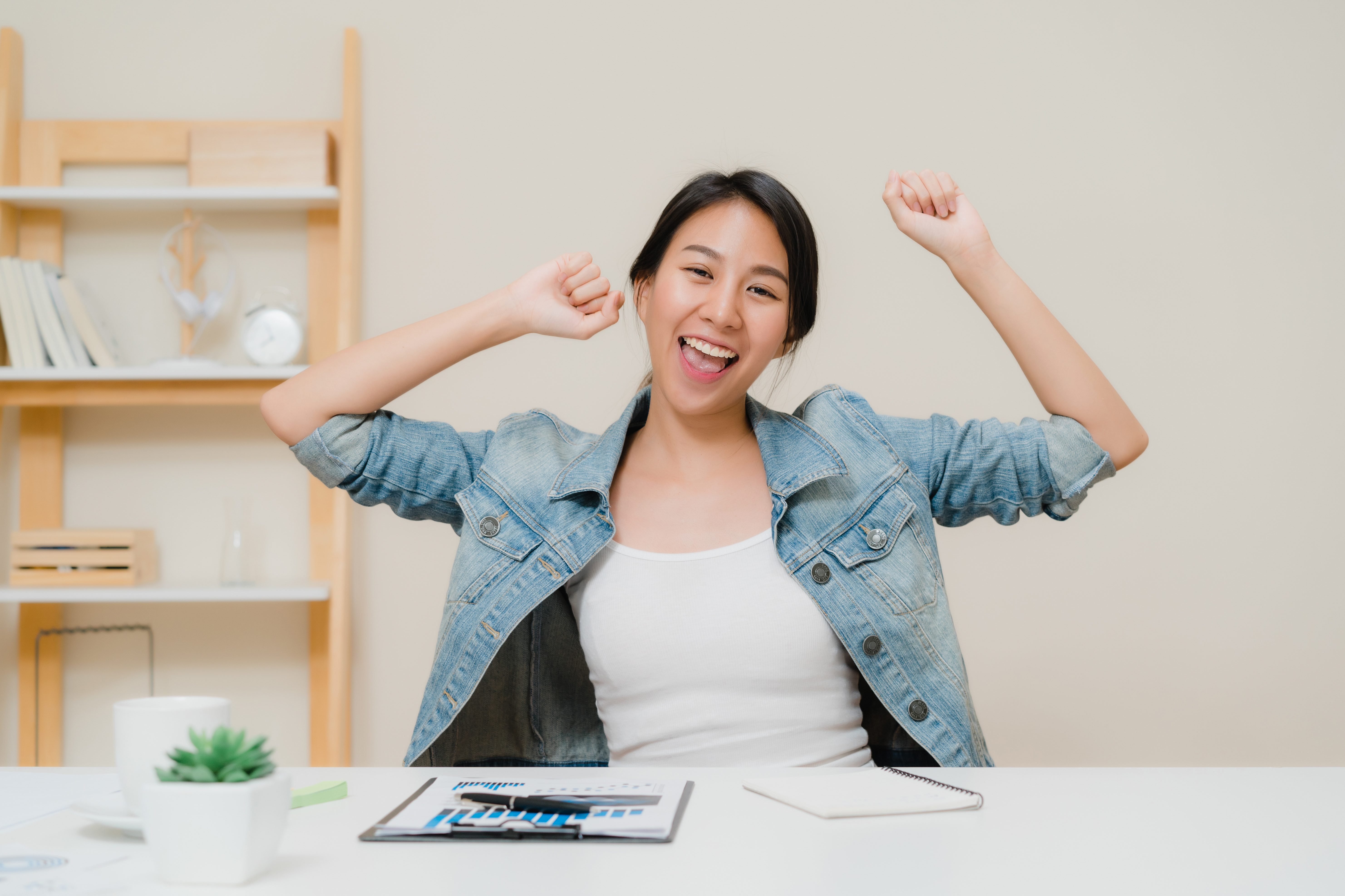 Young asian woman working using laptop on desk in living room at home. Asian business woman success celebration feeling happy dancing at home office<a href="https://www.freepik.com/photos/business">Business photo created by tirachardz - www.freepik.com</a>