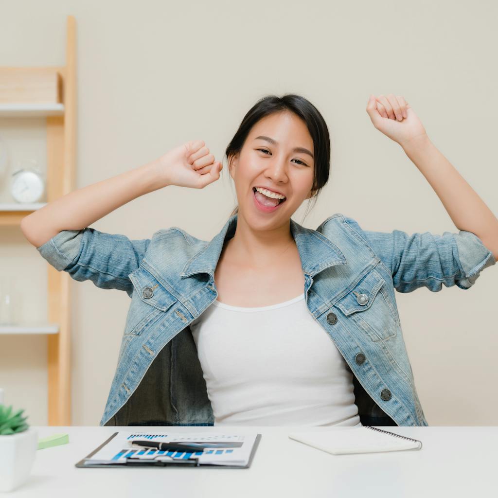 Young asian woman working using laptop on desk in living room at home. Asian business woman success celebration feeling happy dancing at home office<a href="https://www.freepik.com/photos/business">Business photo created by tirachardz - www.freepik.com</a>
