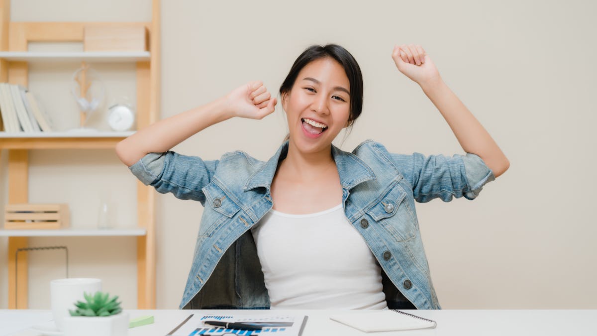 Young asian woman working using laptop on desk in living room at home. Asian business woman success celebration feeling happy dancing at home office<a href="https://www.freepik.com/photos/business">Business photo created by tirachardz - www.freepik.com</a>