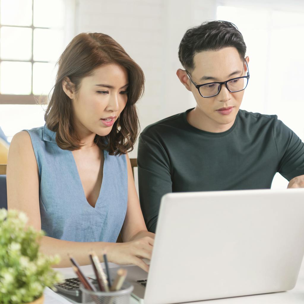 Pareja asiática comprobando el análisis de las facturas de los servicios públicos sentados juntos en casa. <a href="https://www.freepik.com/photos/family">Family photo created by our-team - www.freepik.com</a>