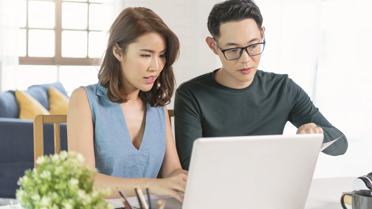 Pareja asiática comprobando el análisis de las facturas de los servicios públicos sentados juntos en casa. <a href="https://www.freepik.com/photos/family">Family photo created by our-team - www.freepik.com</a>