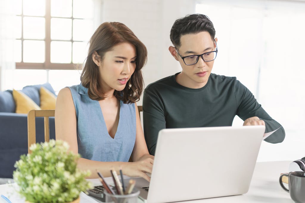 Serious asian husband checking analyzing statement utilities bills sitting together at home. <a href="https://www.freepik.com/photos/family">Family photo created by our-team - www.freepik.com</a>