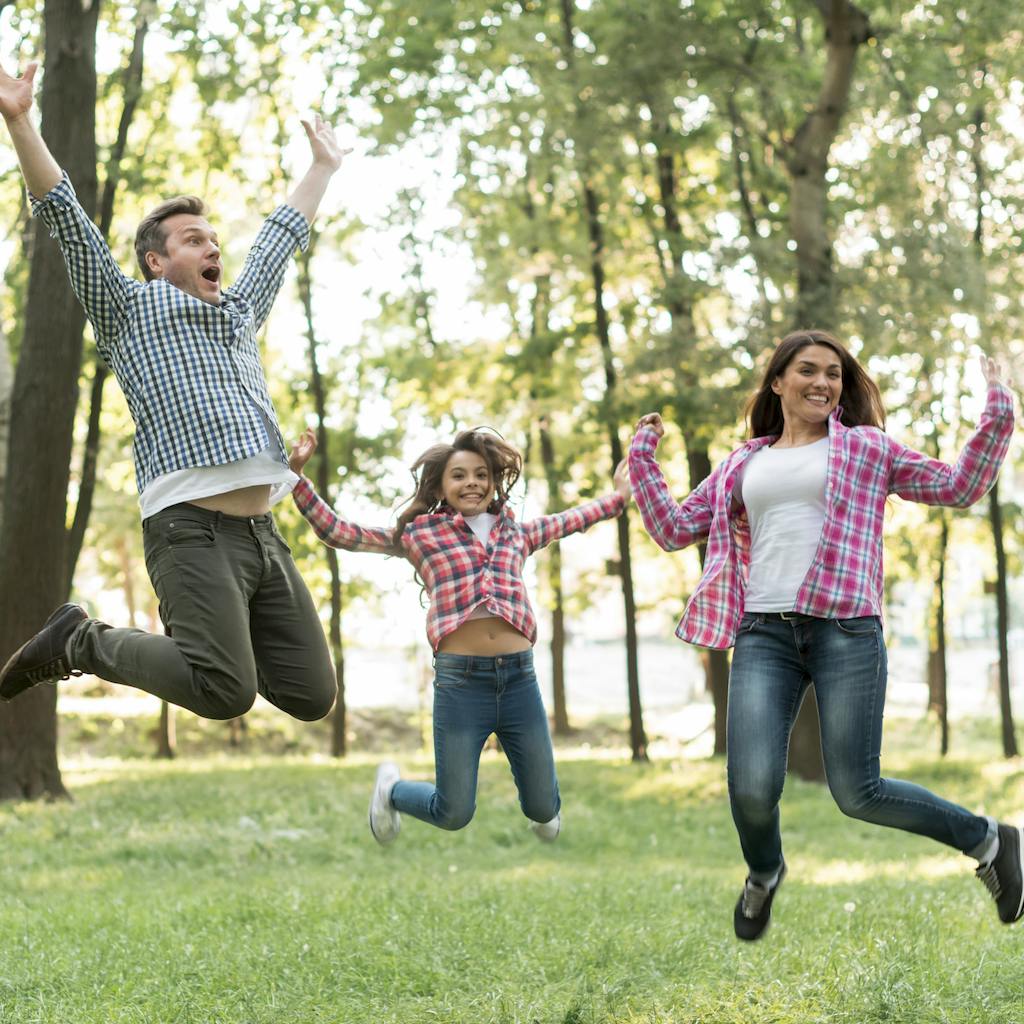 Happy family jumping in green nature <a href='https://www.freepik.com/photos/tree'>Tree photo created by freepik - www.freepik.com</a>